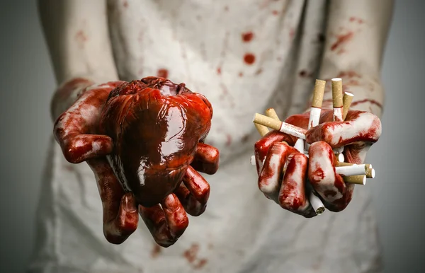 Social advertising and tobacco control: bloody hand holding a cigarette smoker and bloody human heart