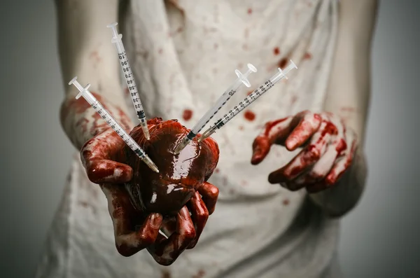 Социальная реклама и борьба с наркоманией: кровожадные руки наркомана, держащего шприц и кровавое человеческое сердце — стоковое фото