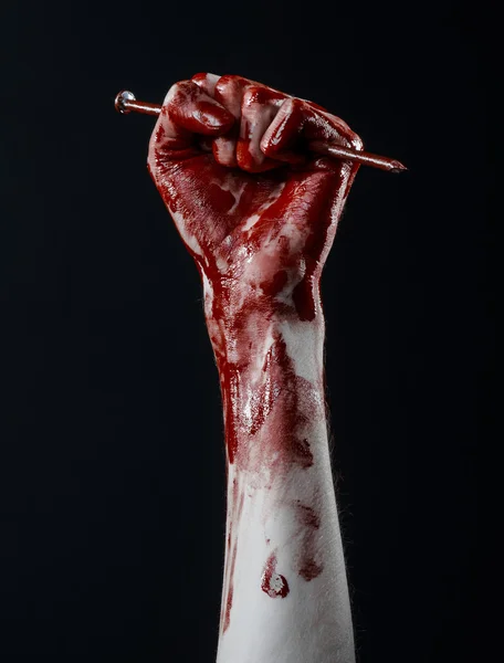 Bloody Halloween tema: mão sangrenta segurando um grande prego afiado isolado no fundo preto no estúdio — Fotografia de Stock