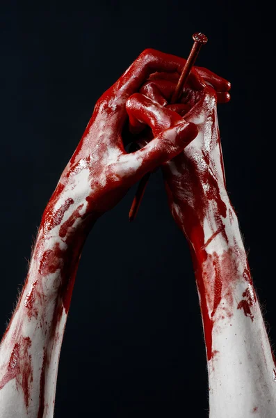 Thème d'Halloween sanglant : main sanglante tenant un grand clou pointu isolé sur fond noir en studio — Photo