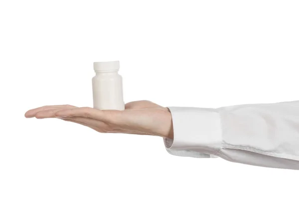Medizinisches Thema: Die Hand des Arztes hält ein weißes leeres Gefäß mit Pillen auf weißem Hintergrund — Stockfoto