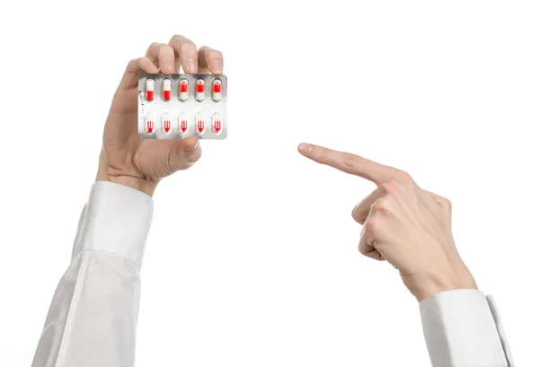 Thème médical : main du médecin tenant une capsule rouge pour la santé sur un fond blanc isolé — Photo