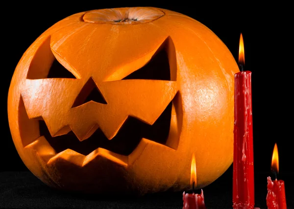 Eng pompoen, jack lantern, pompoen halloween, rode kaarsen op een zwarte achtergrond, halloween thema, pompoen moordenaar — Stockfoto