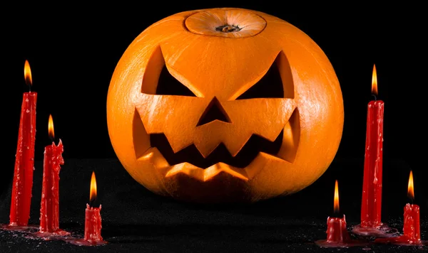 Eng pompoen, jack lantern, pompoen halloween, rode kaarsen op een zwarte achtergrond, halloween thema, pompoen moordenaar — Stockfoto