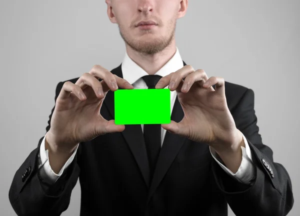 Empresário em um terno preto e gravata preta segurando um cartão, uma mão segurando um cartão, cartão verde, cartão é inserido, o cartão-chave croma verde, fundo cinza, isolado, tema de negócios, tema da banca — Fotografia de Stock