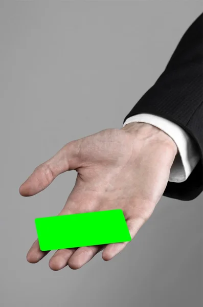 Επιχειρηματία σε ένα μαύρο κοστούμι και εκμετάλλευση μαύρη γραβάτα που τοποθετείτε μια κάρτα, ένα χέρι που κρατά μια κάρτα, πράσινο κάρτα, κάρτα, κάρτα πράσινο chroma-κλειδί, γκρι φόντο, απομονωμένες, επιχειρηματικές θέμα, θέμα των τραπεζικών — Φωτογραφία Αρχείου