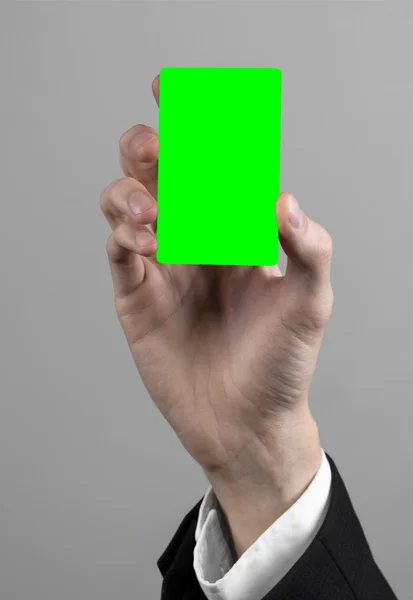 businessman in a black suit and black tie holding a card, a hand holding a card, green card, card is inserted, the green chroma key card, gray background, isolated, business theme, theme of banking