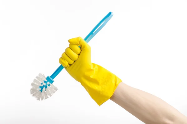 Уборка дома и уборка туалета: человеческая рука с синей щеткой унитаза в желтых защитных перчатках изолирована на белом фоне в студии — стоковое фото
