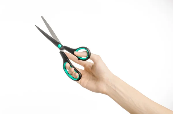 Office and home topic: human hand holding a black scissors with blue accents on a white isolated background in studio — Stock Photo, Image