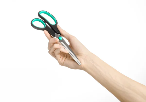 Office and home topic: human hand holding a black scissors with blue accents on a white isolated background in studio — Stock Photo, Image