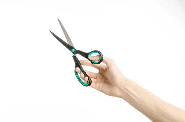 Office and home topic: human hand holding a black scissors with blue accents on a white isolated background in studio — Stock Photo, Image