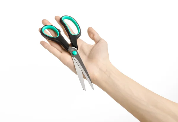 Office and home topic: human hand holding a black scissors with blue accents on a white isolated background in studio — Stock Photo, Image