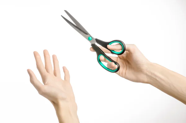 Bureau als huismilieu onderwerp: menselijke hand met een zwarte schaar met blauwe accenten op een witte achtergrond in studio geïsoleerd — Stockfoto