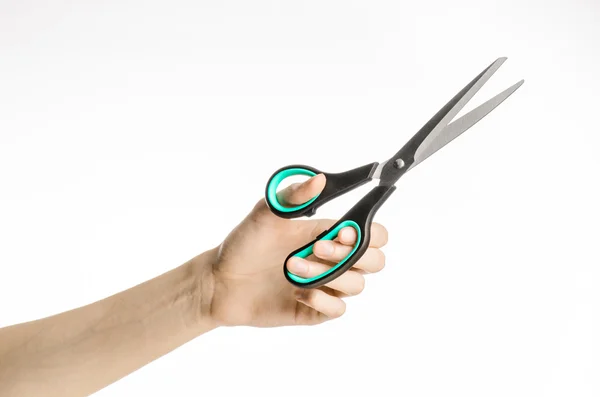 Office and home topic: human hand holding a black scissors with blue accents on a white isolated background in studio — Stock Photo, Image