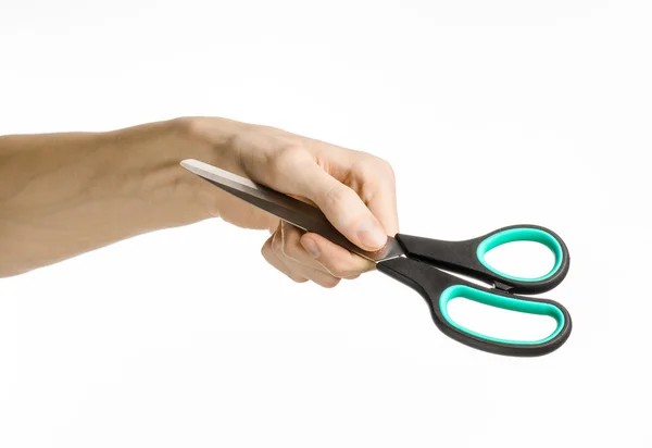 Office and home topic: human hand holding a black scissors with blue accents on a white isolated background in studio — Stock Photo, Image
