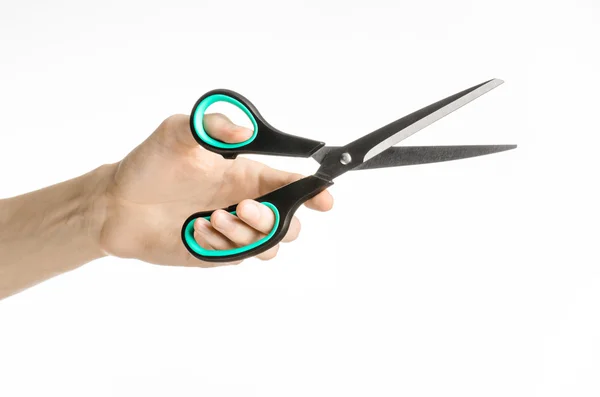 Office and home topic: human hand holding a black scissors with blue accents on a white isolated background in studio — Stock Photo, Image