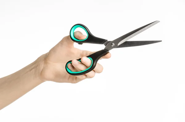 Office and home topic: human hand holding a black scissors with blue accents on a white isolated background in studio — Stock Photo, Image