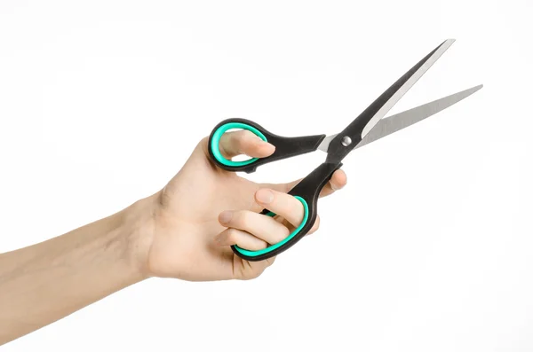 Office and home topic: human hand holding a black scissors with blue accents on a white isolated background in studio — Stock Photo, Image