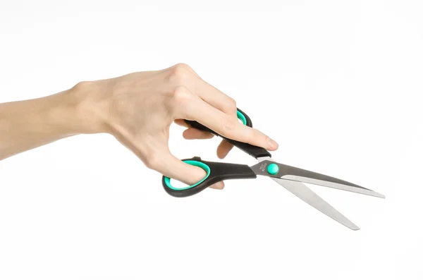 Office and home topic: human hand holding a black scissors with blue accents on a white isolated background in studio — Stock Photo, Image