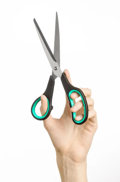 Office and home topic: human hand holding a black scissors with blue accents on a white isolated background in studio — Stock Photo, Image