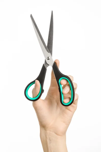 Office and home topic: human hand holding a black scissors with blue accents on a white isolated background in studio — Stock Photo, Image