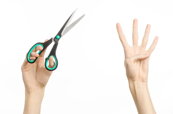 Office and home topic: human hand holding a black scissors with blue accents on a white isolated background in studio — Stock Photo, Image