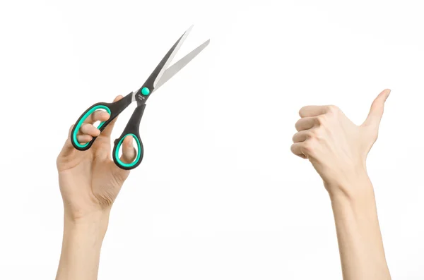 Office and home topic: human hand holding a black scissors with blue accents on a white isolated background in studio — Stock Photo, Image