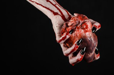 Kanlı korku ve Halloween Tema: korkunç kanlı eller kanlı insan kalbi tutan bir siyah arka plan üzerine siyah çivi ile izole Studio arka plan