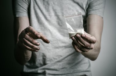 Uyuşturucu ve uyuşturucu bağımlılığı konu karşı mücadele: paket kokain gri T-shirt stüdyoda karanlık bir arka plan üzerine tutarak bağımlısı