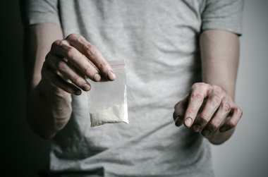 Uyuşturucu ve uyuşturucu bağımlılığı konu karşı mücadele: paket kokain gri T-shirt stüdyoda karanlık bir arka plan üzerine tutarak bağımlısı