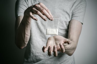 Uyuşturucu ve uyuşturucu bağımlılığı konu karşı mücadele: paket kokain gri T-shirt stüdyoda karanlık bir arka plan üzerine tutarak bağımlısı