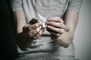 Uyuşturucu ve uyuşturucu bağımlılığı konu karşı mücadele: paket kokain gri T-shirt stüdyoda karanlık bir arka plan üzerine tutarak bağımlısı