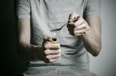 Uyuşturucu ve uyuşturucu bağımlılığı konu karşı mücadele: kaşık daha hafif ve sıvı ilaç içinde karanlık bir arka plan üzerinde bir T-shirt ısıtır tutan bağımlısı
