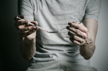 Uyuşturucu ve uyuşturucu bağımlılığı konu karşı mücadele: kaşık daha hafif ve sıvı ilaç içinde karanlık bir arka plan üzerinde bir T-shirt ısıtır tutan bağımlısı