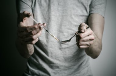 Uyuşturucu ve uyuşturucu bağımlılığı konu karşı mücadele: kaşık daha hafif ve sıvı ilaç içinde karanlık bir arka plan üzerinde bir T-shirt ısıtır tutan bağımlısı