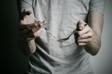 Uyuşturucu ve uyuşturucu bağımlılığı konu karşı mücadele: kaşık daha hafif ve sıvı ilaç içinde karanlık bir arka plan üzerinde bir T-shirt ısıtır tutan bağımlısı