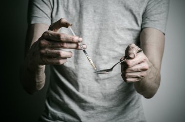 Uyuşturucu ve uyuşturucu bağımlılığı konu karşı mücadele: kaşık daha hafif ve sıvı ilaç içinde karanlık bir arka plan üzerinde bir T-shirt ısıtır tutan bağımlısı