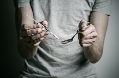 Uyuşturucu ve uyuşturucu bağımlılığı konu karşı mücadele: kaşık daha hafif ve sıvı ilaç içinde karanlık bir arka plan üzerinde bir T-shirt ısıtır tutan bağımlısı