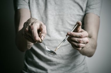Uyuşturucu ve uyuşturucu bağımlılığı konu karşı mücadele: kaşık daha hafif ve sıvı ilaç içinde karanlık bir arka plan üzerinde bir T-shirt ısıtır tutan bağımlısı