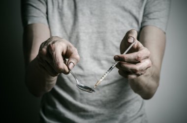 Uyuşturucu ve uyuşturucu bağımlılığı konu karşı mücadele: kaşık daha hafif ve sıvı ilaç içinde karanlık bir arka plan üzerinde bir T-shirt ısıtır tutan bağımlısı