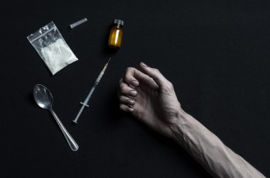 The fight against drugs and drug addiction topic: hand addict lies on a dark table and around it are drugs, a top studio clipart