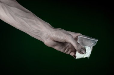 Uyuşturucu ve uyuşturucu bağımlılığı konu karşı mücadele: kirli el çanta bağımlısı kokain stüdyoda koyu yeşil arka plan üzerinde tutarak