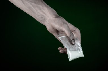 Uyuşturucu ve uyuşturucu bağımlılığı konu karşı mücadele: kirli el çanta bağımlısı kokain stüdyoda koyu yeşil arka plan üzerinde tutarak