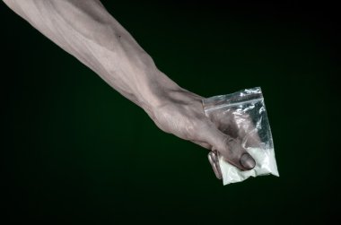 Uyuşturucu ve uyuşturucu bağımlılığı konu karşı mücadele: kirli el çanta bağımlısı kokain stüdyoda koyu yeşil arka plan üzerinde tutarak