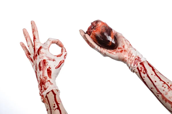 Тема операции и медицины: Кровавый хирург держит человеческое сердце в окровавленных белых перчатках на белом фоне в студии — стоковое фото