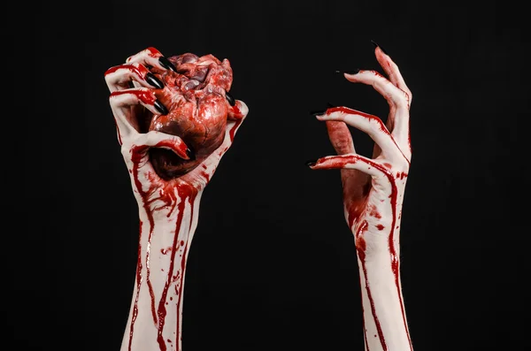 Véres horror és a Halloween téma: szörnyű véres kezek gazdaság egy véres emberi szív, fekete alapon fekete körmök elszigetelt háttér stúdió — Stock Fotó