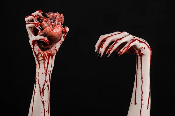 Krvavý horor a Halloween téma: hrozné krvavé ruce s černými nehty drží krvavé lidské srdce na černém pozadí, samostatný pozadí ve studiu — Stock fotografie