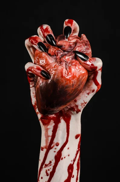 Kanlı korku ve Halloween Tema: korkunç kanlı eller kanlı insan kalbi tutan bir siyah arka plan üzerine siyah çivi ile izole Studio arka plan
