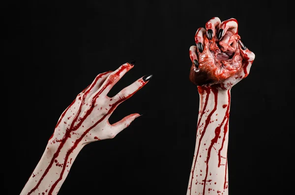 Blutiger Horror und Halloween-Thema: schrecklich blutige Hände mit schwarzen Nägeln, die ein blutiges menschliches Herz auf schwarzem Hintergrund im Studio halten — Stockfoto