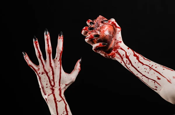血腥的恐怖和万圣节主题: 可怕血腥的双手握着血腥人类心脏在黑色背景上的黑色指甲与孤立在演播室背景 — 图库照片